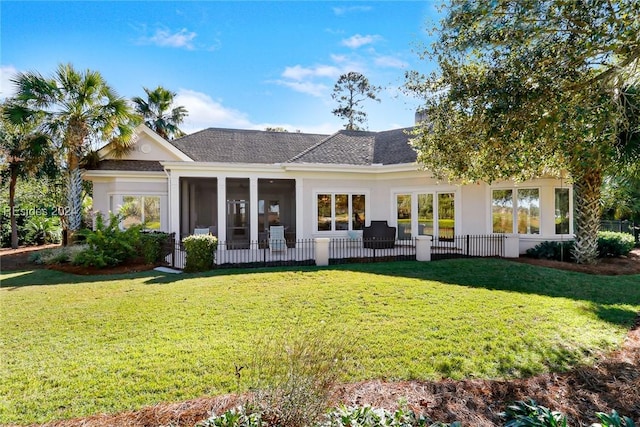 rear view of house with a sunroom and a lawn