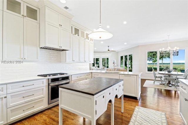 kitchen with hanging light fixtures, stainless steel appliances, a center island, dark hardwood / wood-style flooring, and kitchen peninsula