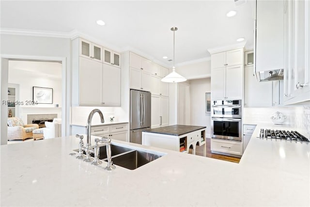 kitchen featuring white cabinetry, sink, decorative light fixtures, and appliances with stainless steel finishes