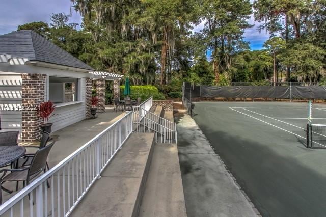 view of tennis court with a patio