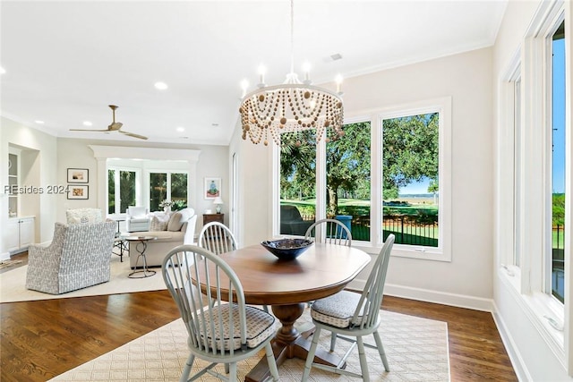 dining room featuring crown molding, wood-type flooring, and ceiling fan with notable chandelier