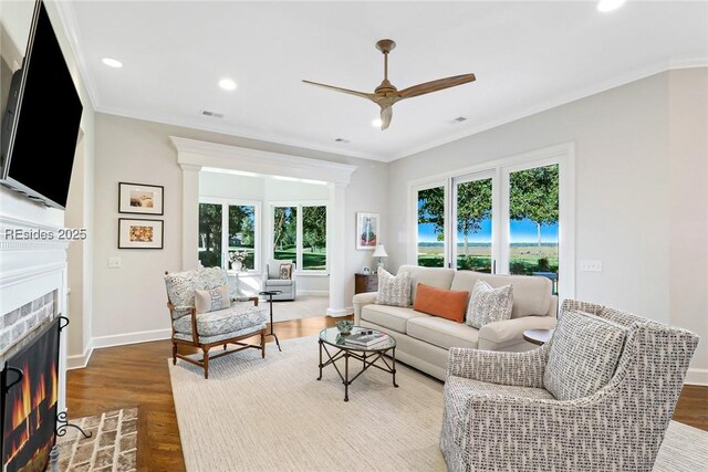 living room with hardwood / wood-style flooring, ornamental molding, and a brick fireplace