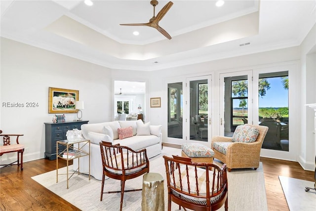 living room featuring crown molding, ceiling fan, a raised ceiling, and hardwood / wood-style floors