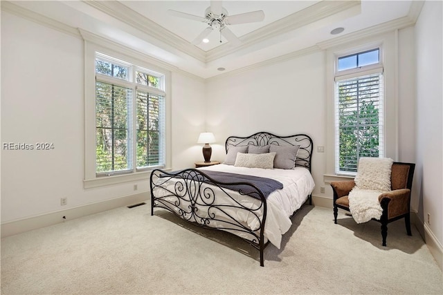 bedroom featuring multiple windows, a raised ceiling, light carpet, and ceiling fan