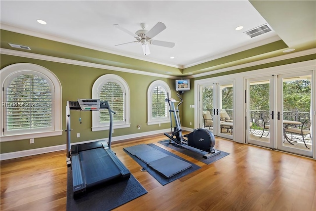 workout room with crown molding, light hardwood / wood-style floors, french doors, and a raised ceiling