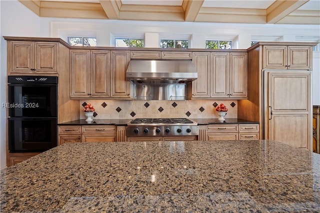 kitchen featuring ventilation hood, stainless steel gas stovetop, dark stone countertops, and double oven