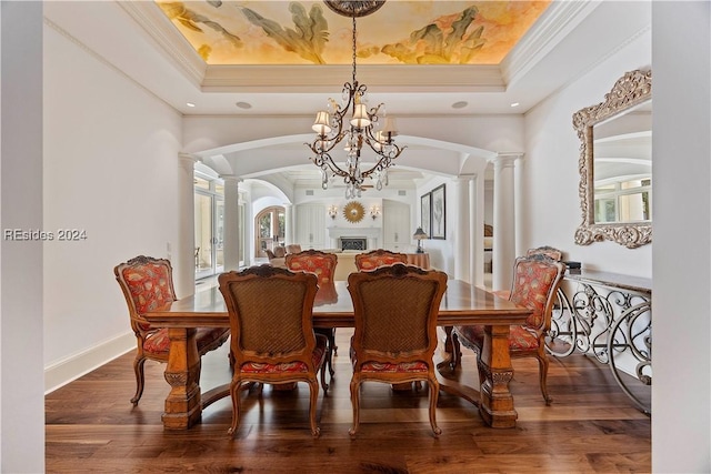 dining space featuring decorative columns, ornamental molding, hardwood / wood-style floors, and a tray ceiling