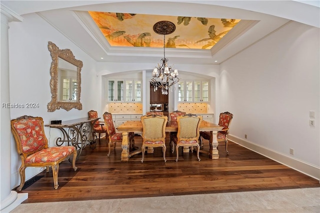 dining room with a tray ceiling, ornamental molding, a chandelier, and hardwood / wood-style flooring