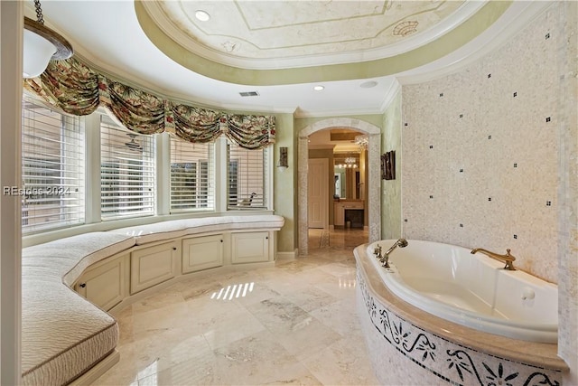 bathroom with ornamental molding, a tray ceiling, and a bathtub