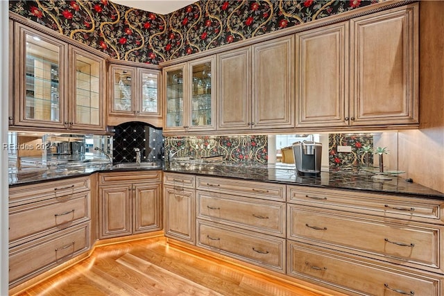 kitchen featuring tasteful backsplash, sink, light hardwood / wood-style flooring, and dark stone countertops