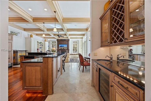 kitchen featuring a kitchen bar, coffered ceiling, sink, decorative light fixtures, and beamed ceiling