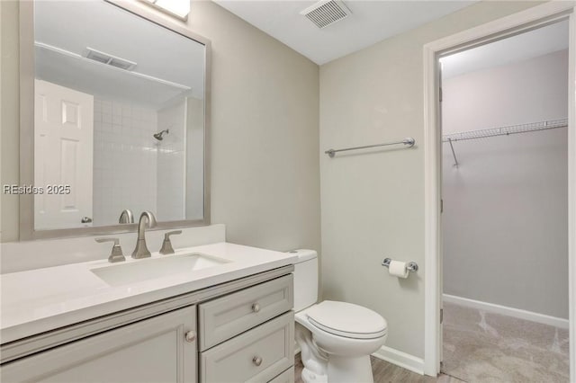 bathroom featuring vanity, toilet, and a tile shower