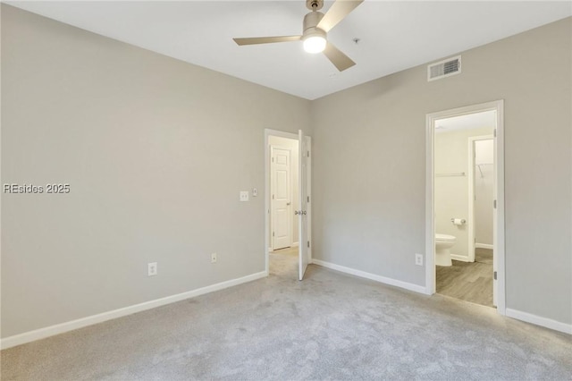 unfurnished bedroom featuring ceiling fan, ensuite bathroom, a spacious closet, light colored carpet, and a closet