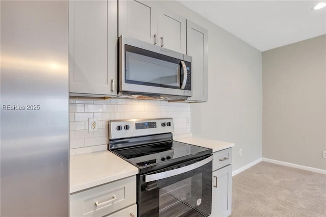 kitchen featuring tasteful backsplash, light colored carpet, and appliances with stainless steel finishes