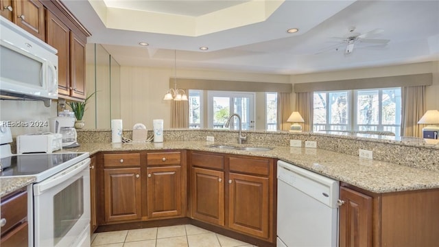 kitchen with white appliances, a healthy amount of sunlight, a raised ceiling, and sink