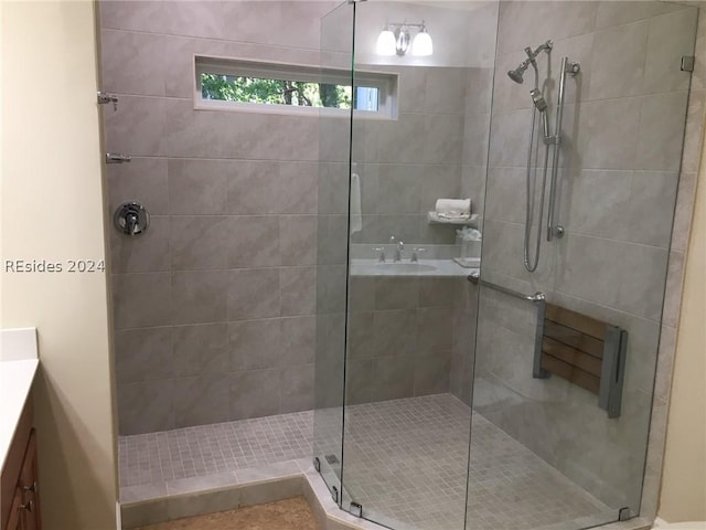 bathroom featuring a shower with door and vanity