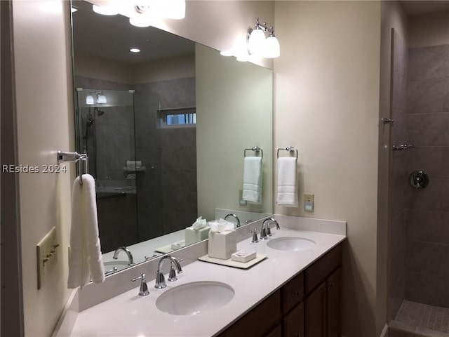 bathroom with a tile shower and vanity