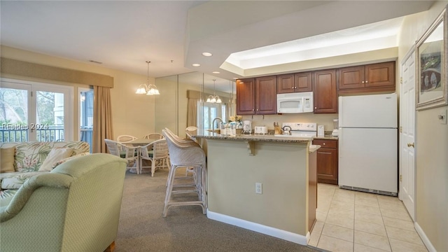 kitchen featuring light tile patterned flooring, pendant lighting, a breakfast bar area, light stone countertops, and white appliances