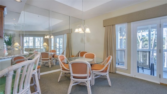 carpeted dining area with an inviting chandelier and a raised ceiling