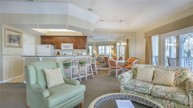 carpeted living room with a raised ceiling and a notable chandelier