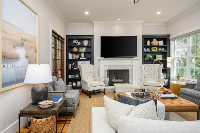 living room with crown molding, wood-type flooring, a fireplace, and built in features