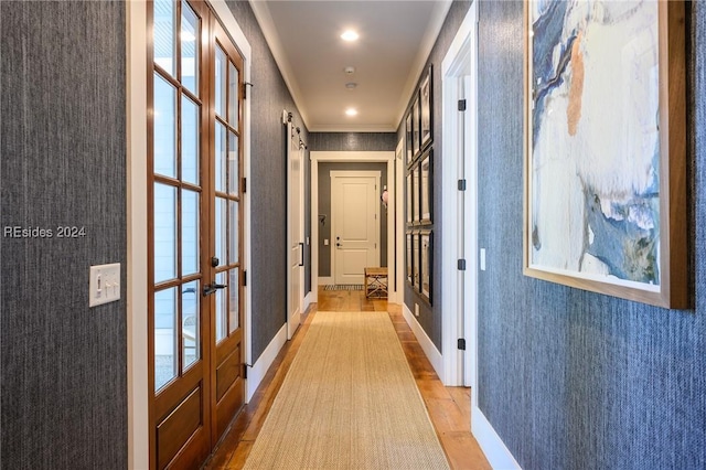 hall with french doors, crown molding, and light hardwood / wood-style floors