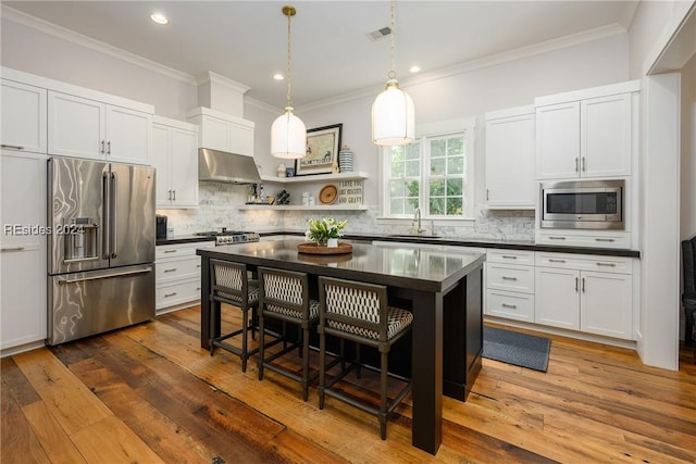 kitchen featuring a kitchen island, appliances with stainless steel finishes, a breakfast bar, sink, and white cabinets