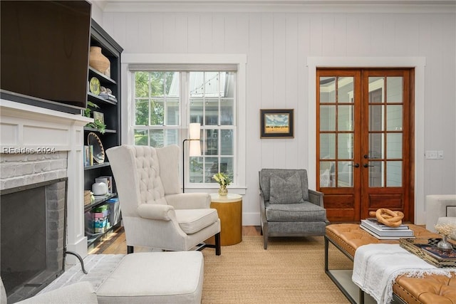 living area with a brick fireplace, light colored carpet, and french doors