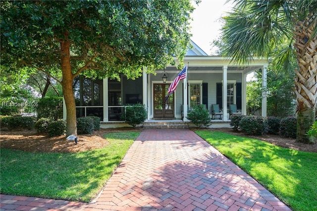 view of front of house featuring a front yard, french doors, and covered porch