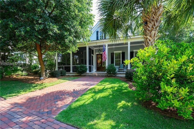 view of front facade with covered porch, a sunroom, and a front yard