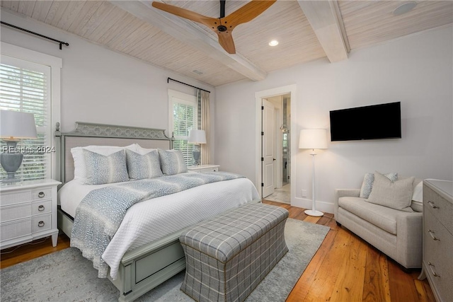 bedroom featuring ceiling fan, wood-type flooring, beam ceiling, and multiple windows