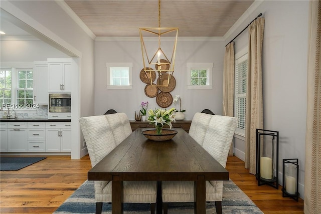 dining area featuring hardwood / wood-style floors, ornamental molding, and sink