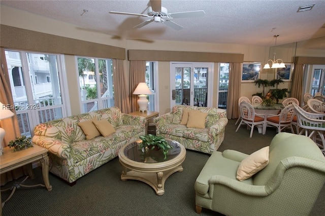 carpeted living room featuring ceiling fan with notable chandelier and a textured ceiling