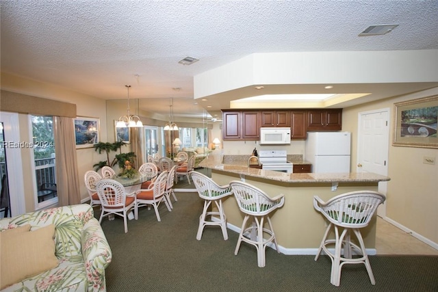 kitchen featuring a chandelier, a kitchen breakfast bar, hanging light fixtures, kitchen peninsula, and white appliances