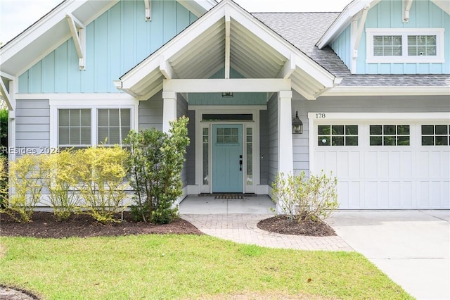 view of exterior entry featuring a garage and a lawn