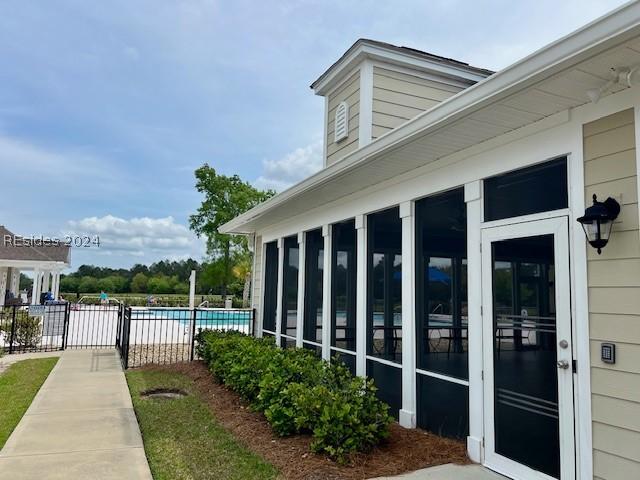 view of property exterior with a fenced in pool and a sunroom