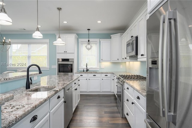 kitchen with appliances with stainless steel finishes, sink, white cabinets, and decorative light fixtures