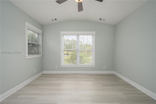 spare room with lofted ceiling, plenty of natural light, and light hardwood / wood-style floors