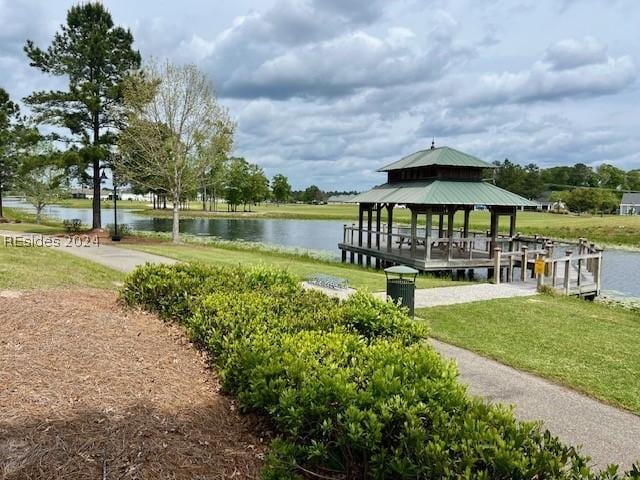 dock area with a gazebo, a water view, and a yard