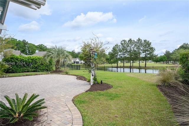 surrounding community featuring a water view, a patio, and a lawn