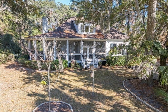 rear view of property featuring a lawn and a sunroom