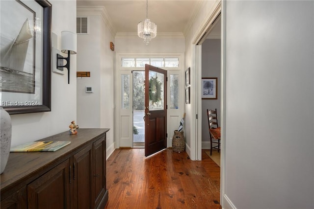 entrance foyer with ornamental molding, an inviting chandelier, and dark hardwood / wood-style flooring