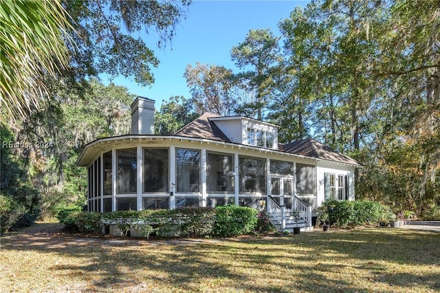 rear view of property featuring a lawn and a sunroom