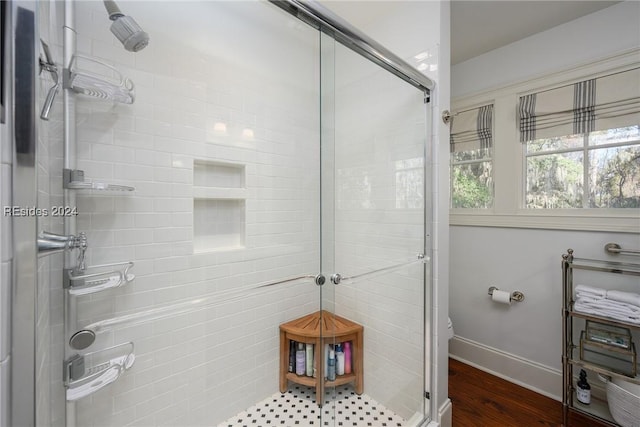 bathroom with wood-type flooring, toilet, and a shower with shower door