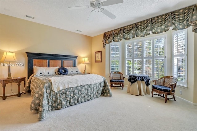 bedroom with ceiling fan, carpet, and a textured ceiling