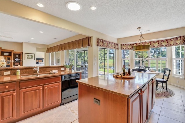 kitchen with light tile patterned floors, sink, hanging light fixtures, black dishwasher, and a kitchen island