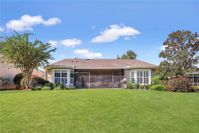 rear view of property featuring a sunroom and a lawn