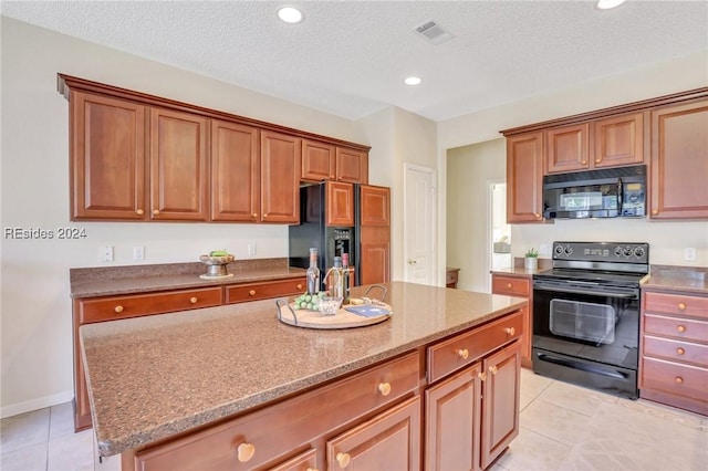 kitchen featuring light tile patterned floors, black appliances, a textured ceiling, and a kitchen island