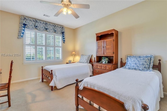 carpeted bedroom featuring ceiling fan and a textured ceiling