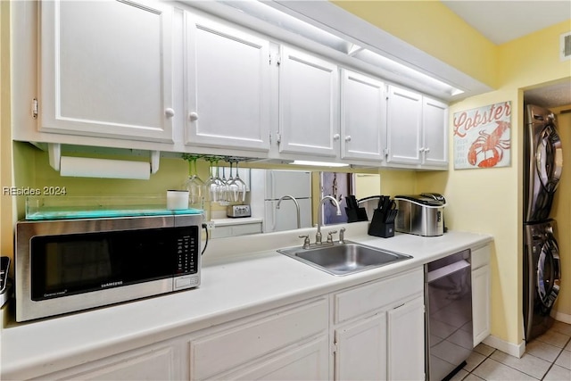 kitchen with white cabinetry, sink, stainless steel appliances, and stacked washing maching and dryer